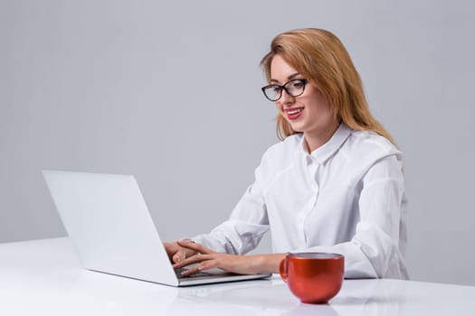 Young businesswoman working at laptop computer. she smiles, prints and looking at monitor