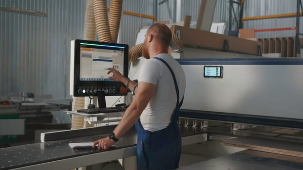 Man clicks on control panel. Creative. Man with beard in work uniform at factory. Man adjusts control panel of industrial machines.