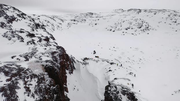 Top view of group of people in mountain pass in winter. Footage. Panorama of tourists traveling between mountain rocks in winter.