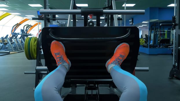 Close up shoes of a fit young woman doing leg press in the gym. Closeup of a fit young woman doing leg presses in the gym. Young beautiful women doing weight lifting at gym. Woman's leg press HD