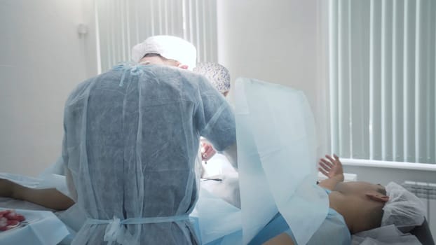 Surgeons perform operation under anesthesia. Action. Two professional surgeons perform operation under anesthesia in abdominal area. Removal of appendicitis or tumour in abdomen.