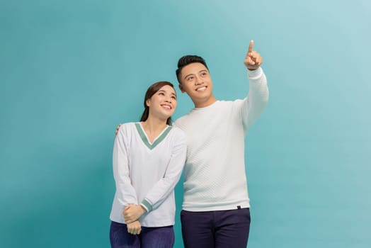 Young asian couple pointed sided on blue banner background