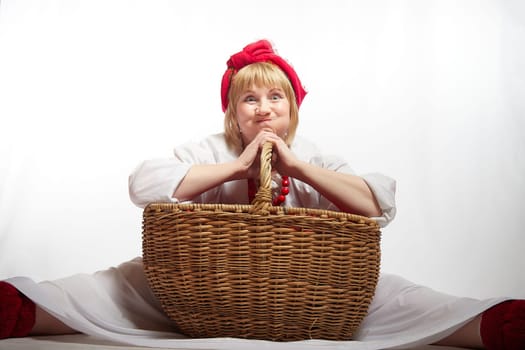 Cheerful funny adult mature woman solokha in a red knitted shawl. Female model in clothes of national ethnic Slavic style. Stylized Ukrainian, Belarusian or Russian woman poses in comic photo shoot