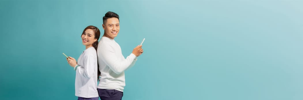 image of asian couple holding smartphone, isolated on blue background