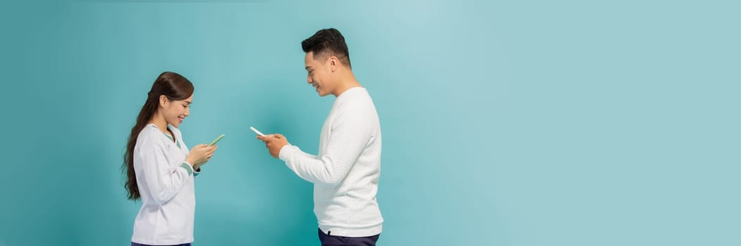 Internet addicted. Two young lovers are busy at their mobile phones in social nets on blue banner