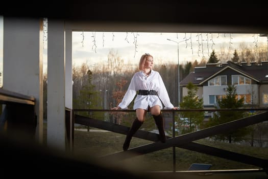 Beautiful redhead moden girl working by laptop in gazebo on autumn, summer or spring day. Businesswoman, student, freelancer or manager works outdoors in natural landscape in a village, city or town