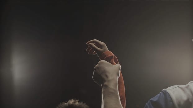 Rear view of the referee who raises the winner's hand. The referee raises the hand of the boy winner in the ring.