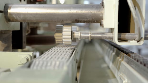 Close-up of machine for rolling parts. Action. Automated machine with rotating gears for rolling products. Industrial enterprise with new machines for processing wood products.