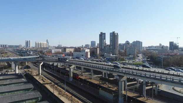Top view of big city with high-rise buildings and traffic on roads. Scene. Beautiful metropolis in daytime is immersed in bustling traffic on roads of city.