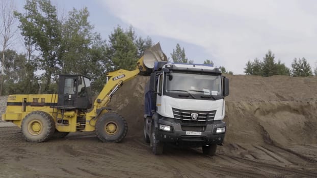 Berlin - Germany, december 6, 2022: Construction digger machine loading truck with sand. Scene. Heavy equipment for digging the ground