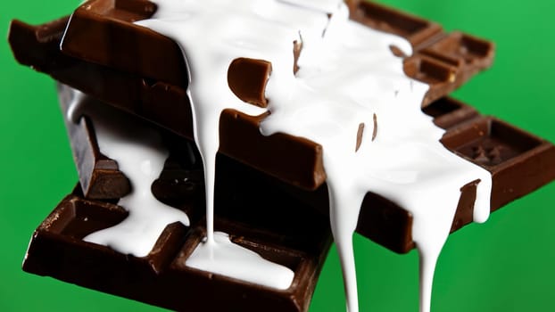 Close up of chocolate bars with draining white glaze isolated on chroma key green wall background. Stock clip. Black chocolate and white glaze
