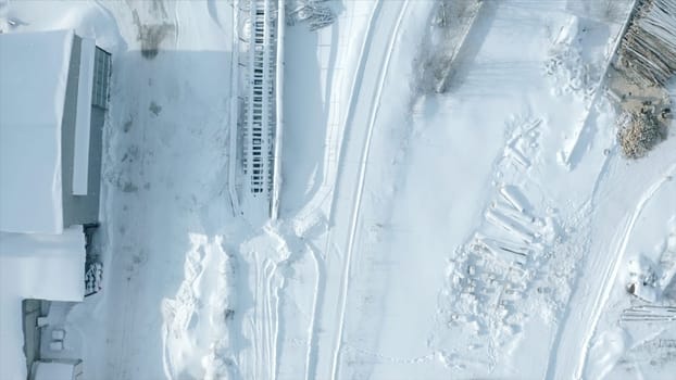 Top view of railway with snow. Clip. Empty snow-covered railway rails in winter. Snow falling on sunny day on railway.
