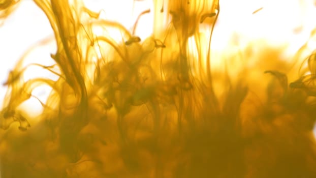 Close up for colored ink spreading in water on white background. Colorful, yellow abstract smoke falling from top to down