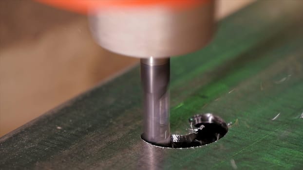 Hole being drilled into metal. Drilling closeup in metal workshop. Employee drill in flat steel plate with bench drill. Industry in slow motion HD