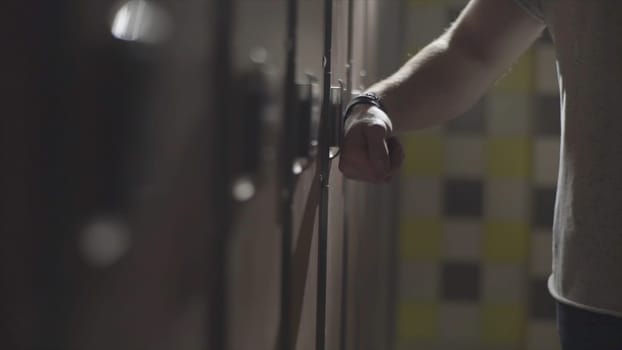 Man's hand opening locker with electric key on his wrist at gym in the changing room. Close up hand opening the locker door in the changing room of a gym.