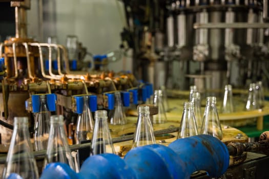 Empty glass bottles on a conveyor showcase the modern distillery's alcoholic beverage manufacturing. Clean automated machinery promises efficient production and bottling.