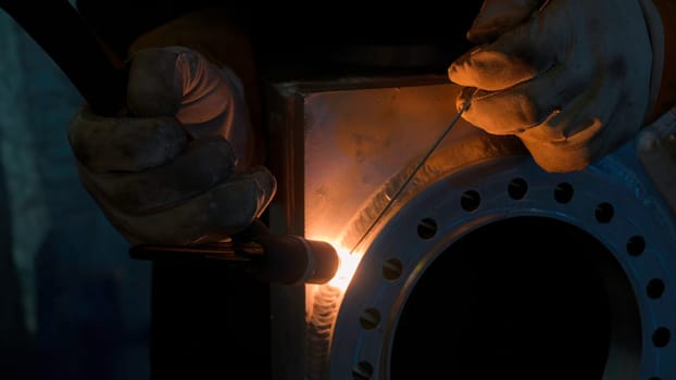 Close up of blacksmith welder in protective uniform works with metal steel and iron using a welding machine. Creative. Bright sparks and flashes, heavy industry concept
