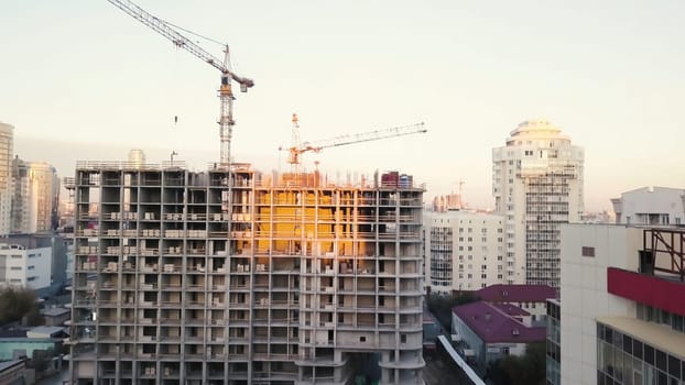 Construction site with cranes. Video. Construction workers are building. Aerial view. Top view of the construction site in the city. Construction in the city with a crane manipulator.