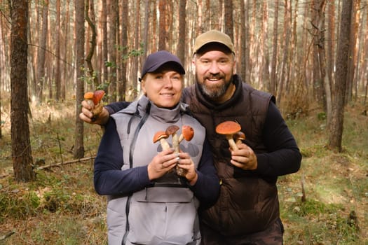 Two mushroom pickers in the forest are holding aspen trees in their hands. Mushrooms in the forest. Mushroom picking.