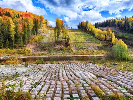 Rows of concrete cubes or rectangles on the bank of river with grass. Breakwaters, protection from water in nature. Background, texture, location