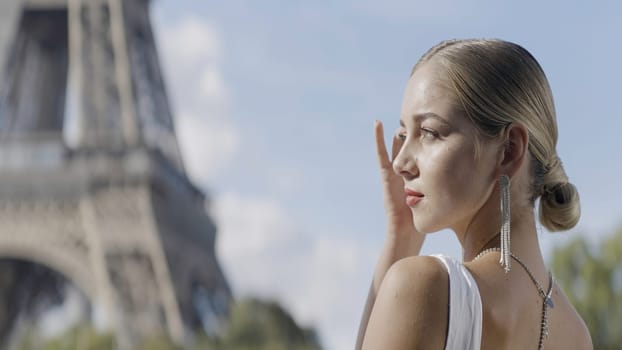 Beautiful model in Paris. Action. A lovely woman with a white hairstyle that has long silver earrings on a summer background. High quality 4k footage