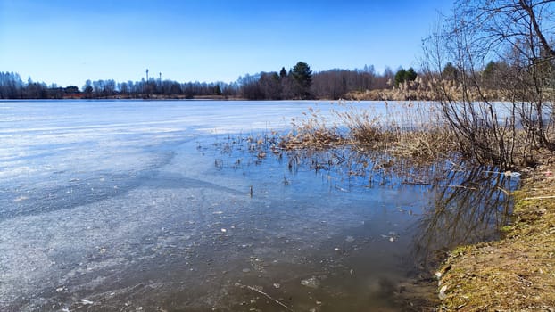 Landscape with a lake covered with ice before the start of melting and ice drift on spring day with the sun. Blue ice and water under sunlight in early spring or autumn