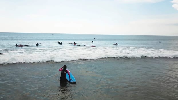 Surfing girl on surfboard on sunrise in the ocean. People ride good wave. Modern active sport lifestyle and summer vacation. People riding boards on the waves.