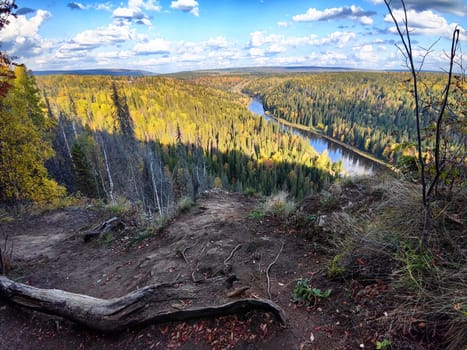 View from height on beautiful amazing landscape with trees, greenery, river below, distant horizon and blue sky with white clouds. Nature in the mountains or hills. The concept of freedom and travel