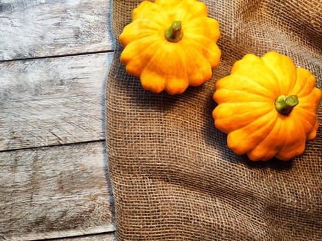 Yellow pattison on wooden boards of table and on fabric is sackcloth or burlap. Healthy Delicious Beautiful Vegetable in autumn. Abstract Background, texture, frame, place for text and copy space