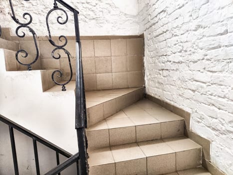Staircase with stone steps, carved wrought iron railings and brick walls. Location, interior inside