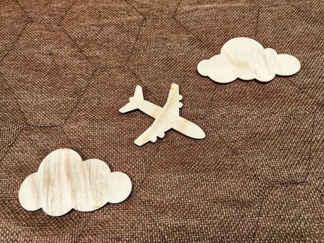 Wooden toy airplane and clouds on a brown background. The concept of traveling by plane. Tourism, travel, speed. Takeoff, landing. The crash, the storm