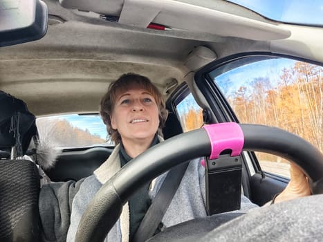 Portrait of female driver in solo journey. Adult mature woman holding steering wheel and looking through windscreen in travel by vehicle on vacation. Lady girl who is owner or rent car for travel