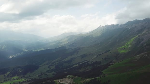 Green mountain covered with forest on the blue sky background. Top view of the mountainous landscape covered in forest in summer day.