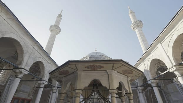 Turkey, Istanbul - July 14, 2022: Beautiful mosque with minarets as historical monument. Action. Bottom view of courtyard of mosque with towering minarets. Beautiful minarets rise into clear sky. Architectural heritage of Istanbul.