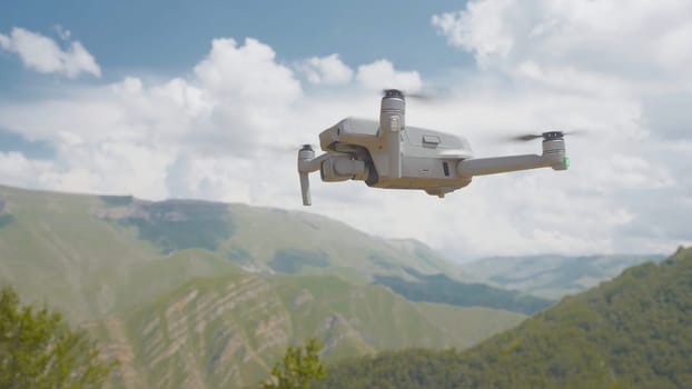 Quadcopter flies on background of mountains. Action. Quadcopter flies and shoots beautiful mountain landscapes. Quadrocopter takes pictures of green mountain valley.