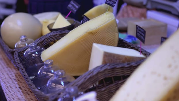 Assorted cheese is on the counter at the fair. ART. Selling homemade cheese lying in baskets at the fair. Cheese collection close-up
