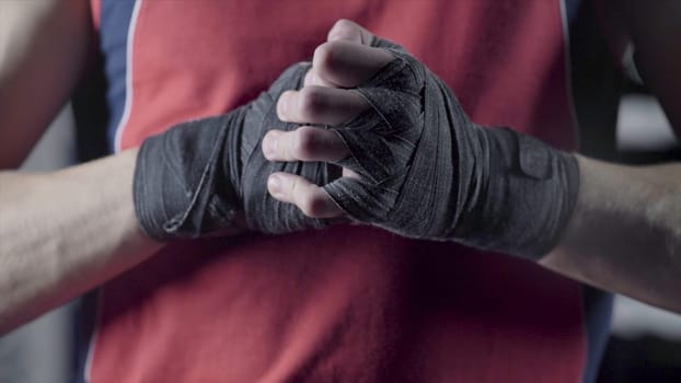 Man flexing his fists before a fight. Close-up of a young Thai boxer hands hemp ropes are wrapped before the fight or training.