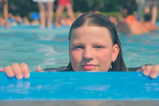 A picture of a little girl at a swimming pool in summer. A young girl looking over the edge of a pool at a swimming pool. Concept of summer, water fun, sun and relaxation.