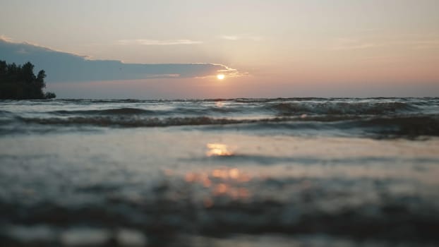 Sun above waving river and shore. Creative. Cloudy sky and rippling water, close up