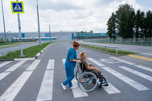 Profile of a nurse helping an elderly woman in a wheelchair cross the road