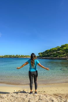 latina woman, on the shore of the beach looking at the sea breathing deeply,