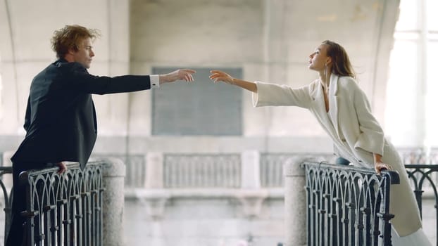 Couple reaches out to each other. Action. Romantic couple reach out with their hands at distance. Elegant couple are stretching on different sides of bridge.