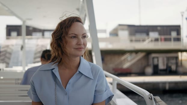 Portrait of a young happy woman with curly hair being blown by the wind. Action. Female traveler on a yacht before the trip