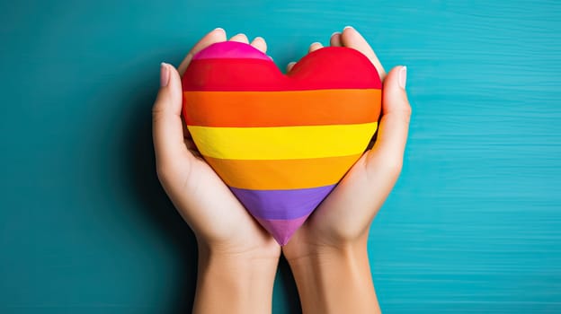 Woman hands holding LGBTQ rainbow community heart flag with rainbow colors.