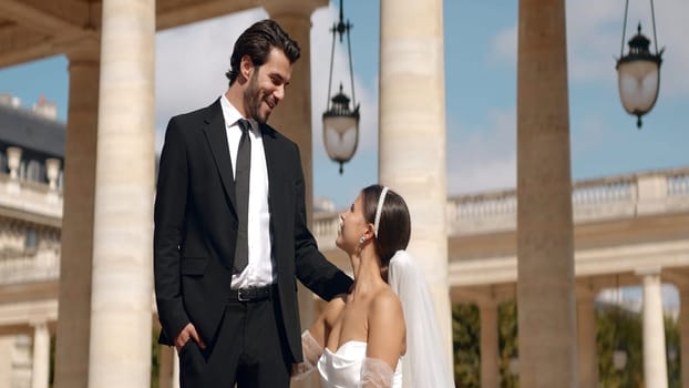 Beautiful couple of newlyweds at photo shoot on sunny day. Action. Attractive couple of newlyweds posing on background of old architecture. Couple of newlyweds with sunny summer day.