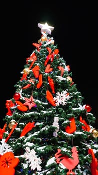 Festive Christmas Tree Illuminated with Twinkling Lights on a Black Background. Vertical photo