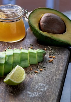 Fresh organic sliced avocado and Sliced avocado halves with lime slice on a wooden cutting board served with Honey on wood table. Healthy food concept, Space for text, Selective Focus.