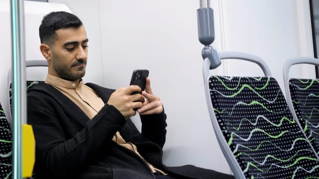 Handsome man in public transport with a smartphone in his hands. Media. Young man in empty bus sitting and typing a message