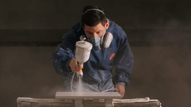 Worker paints wooden board with spray gun. Creative. Worker paints wooden product with spray gun in workshop. Painting workshop for painting wooden products.
