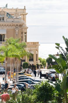 Monaco, Monte-Carlo, 21 October 2022 - Square Casino Monte-Carlo at sunny day, wealth life, tourists take pictures of the landmark, pine trees, blue sky. High quality photo